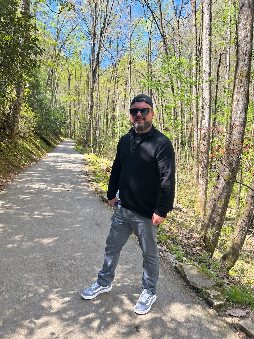 Brian Hanson standing on a sunlit wooded trail
